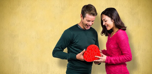 Feliz jovem casal com forma de coração presente — Fotografia de Stock