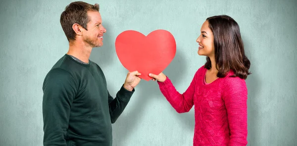 Couple souriant tenant forme de coeur rouge — Photo