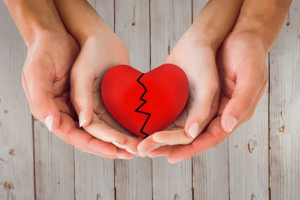 Couple holding broken heart in hands — Stock Photo, Image
