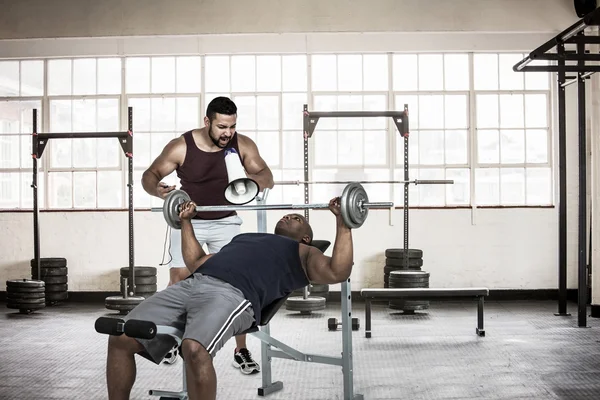 Entraîneur aidant l'homme musculaire — Photo