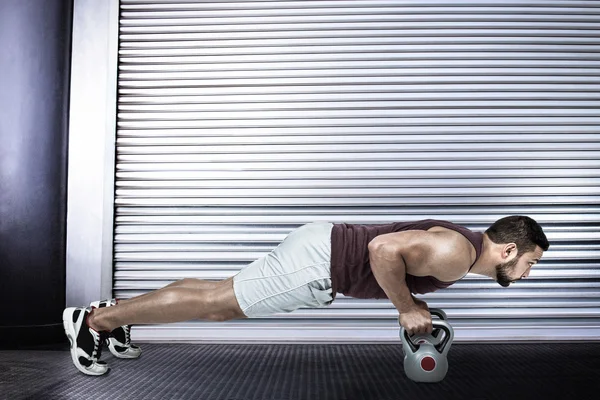 Μυώδης άνδρας κάνει push ups με kettlebells — Φωτογραφία Αρχείου