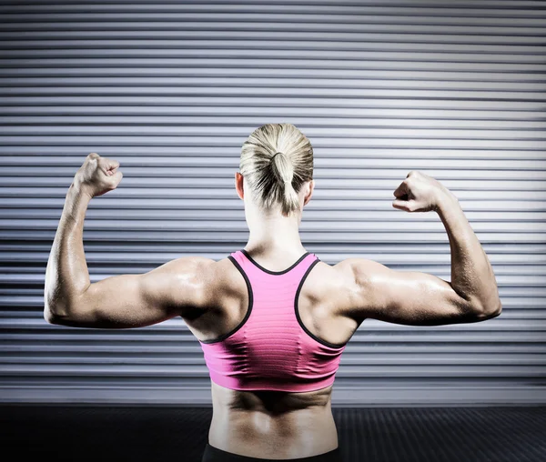 Mujer musculosa flexionando sus brazos — Foto de Stock