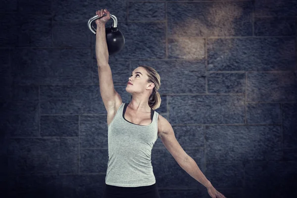 Femme musculaire sérieuse soulevant kettlebell — Photo