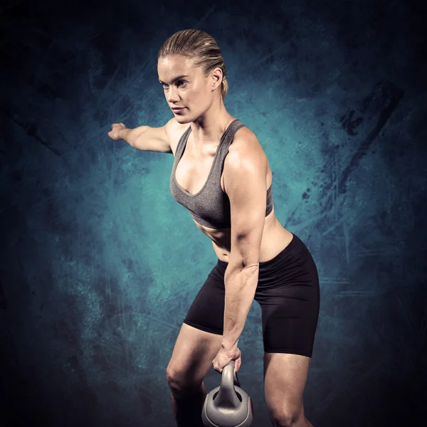 Gespierde vrouw swingende zware kettlebell — Stockfoto