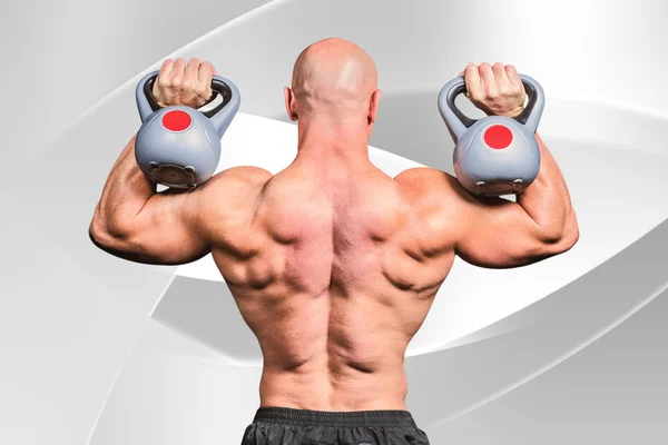 Vista posteriore di calvo uomo sollevamento kettlebells — Foto Stock