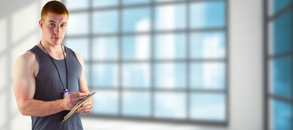 Fit personal trainer writing on clipboard — Stock Photo, Image