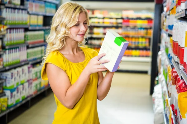 Lachende mooie blonde vrouw lezen een doos — Stockfoto