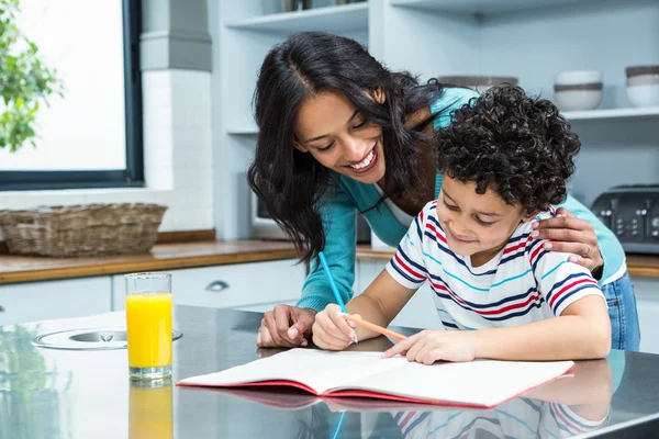 Freundliche Mutter hilft ihrem Sohn bei den Hausaufgaben — Stockfoto