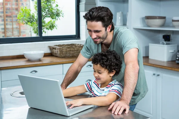 Lachende vader met behulp van de laptop met zijn zoon — Stockfoto