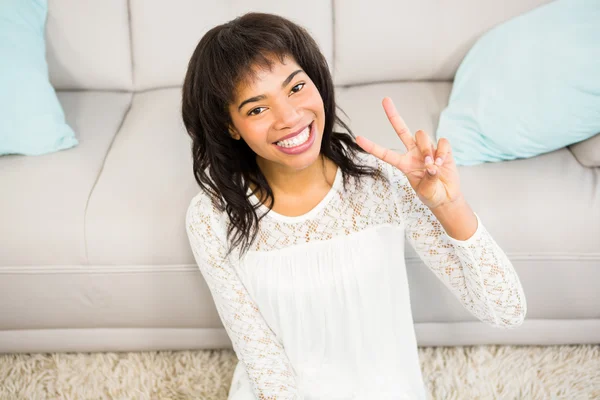 Lässig lächelnde Frau gestikuliert Friedenszeichen — Stockfoto