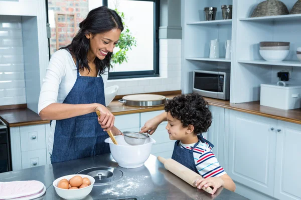 Sorridente madre cucina con suo figlio — Foto Stock