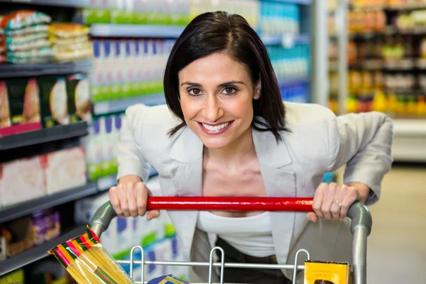 Femme souriante poussant chariot dans l'allée — Photo