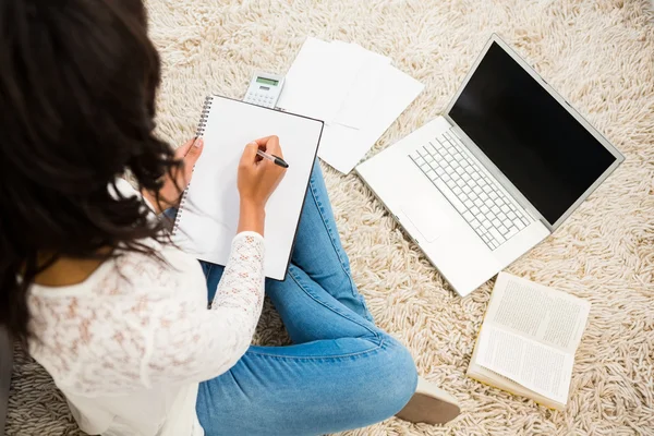 Woman writing note while using her laptop — Stock Photo, Image