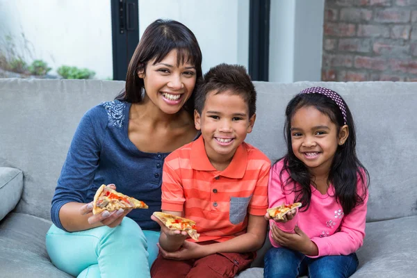 Familia feliz comiendo pizza en el sofá — Foto de Stock