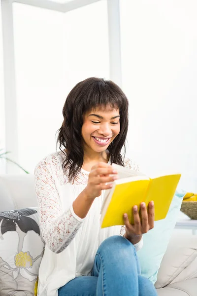 Mujer sonriente casual leyendo un libro amarillo —  Fotos de Stock