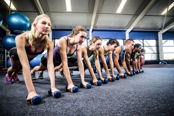 Fitness class in plank position with dumbbells — Stock Photo, Image