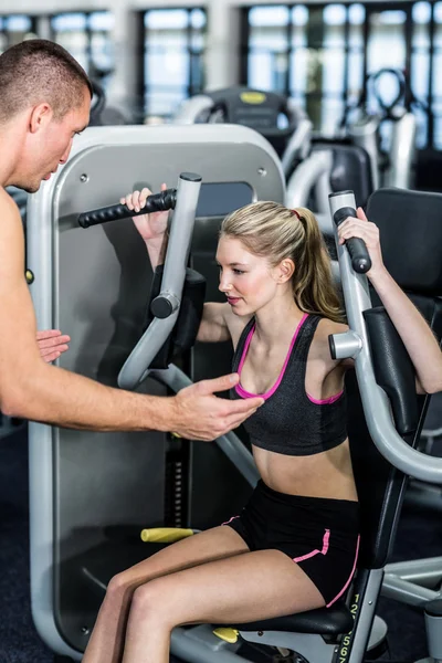 Entrenador que motiva a la mujer mientras usa la máquina de ejercicio —  Fotos de Stock