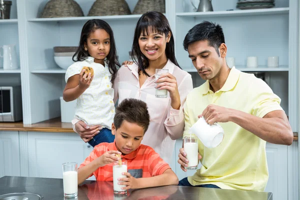 Família feliz comer biscoitos e beber leite — Fotografia de Stock