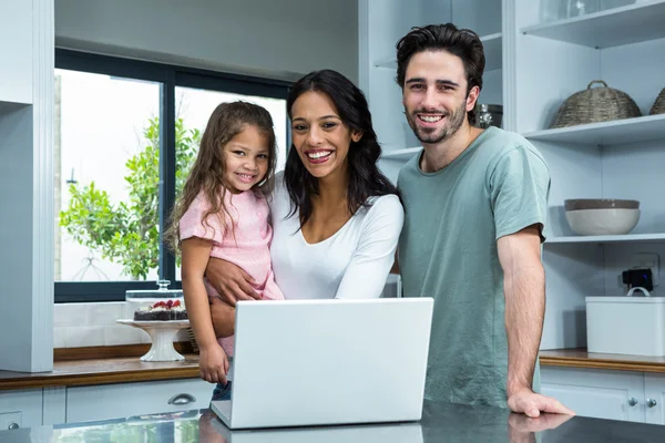 Sonrientes padres usando laptop con hija —  Fotos de Stock