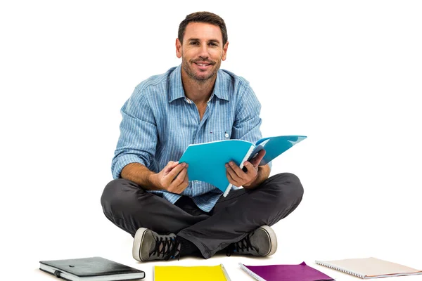 Retrato del hombre sentado en el suelo sujetando el bloc de notas — Foto de Stock