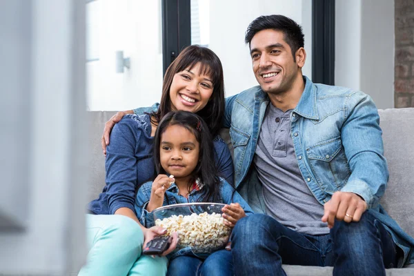 Uśmiechnięta rodzina jedzenia popcorn podczas oglądania telewizji — Zdjęcie stockowe