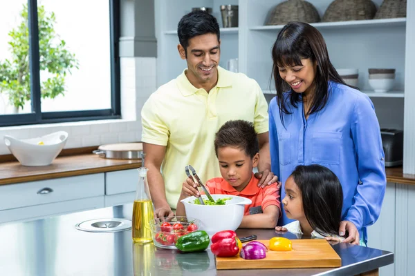 Lycklig familj förbereder sallad i köket — Stockfoto