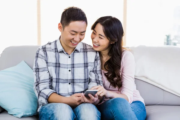 Joven pareja feliz usando el teléfono inteligente — Foto de Stock