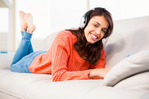 Mulher sorridente ouvindo música enquanto usa seu tablet — Fotografia de Stock