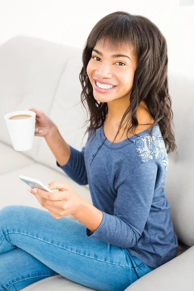 Kvinna anläggning kaffe och smartphone — Stockfoto