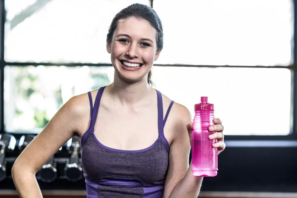 Donna sorridente con bottiglia d'acqua in posa — Foto Stock