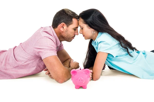 Paar tot op de vloer oog in oog met spaarpot — Stockfoto