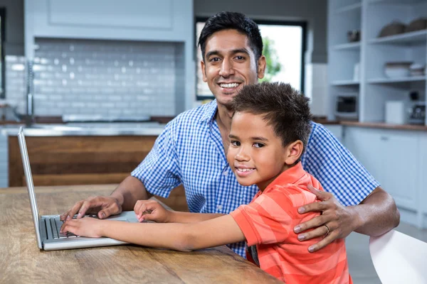 微笑着的父亲与他的儿子使用笔记本电脑 — 图库照片