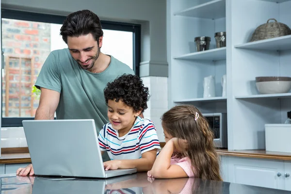 Sorrindo pai e filhos usando laptop — Fotografia de Stock
