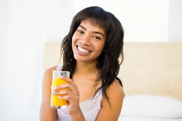 Mujer sonriente casual sosteniendo un vaso de jugo de naranja —  Fotos de Stock