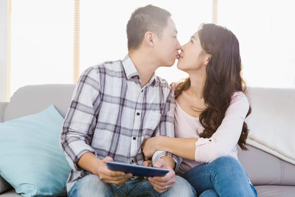 Casal beijando e segurando tablet digital em casa — Fotografia de Stock