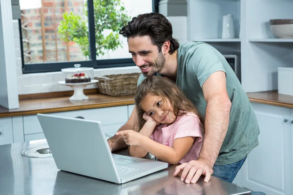 微笑着的父亲和女儿在厨房里用笔记本电脑 — 图库照片