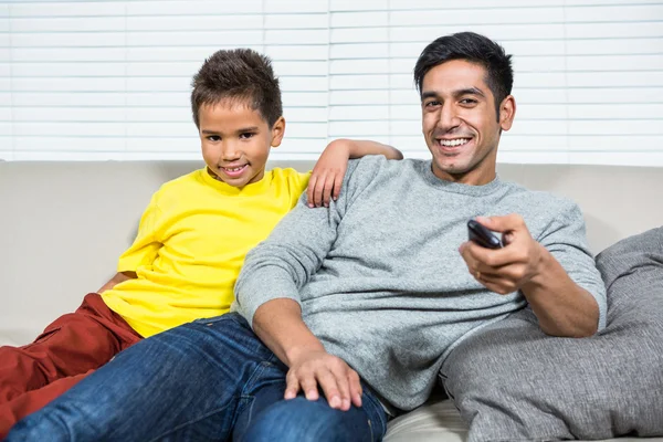 Sonriendo padre e hijo viendo la televisión en el sofá —  Fotos de Stock