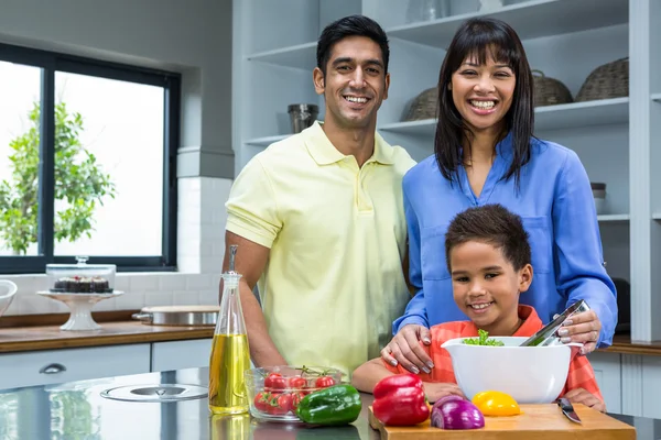 Счастливая семья готовит салат на кухне — стоковое фото
