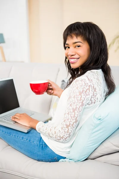 Mujer sonriente con taza de café usando portátil — Foto de Stock