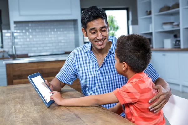 Улыбающийся отец использует планшет со своим сыном — стоковое фото