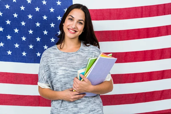 Retrato de una mujer sonriente de pie contra la bandera estadounidense — Foto de Stock