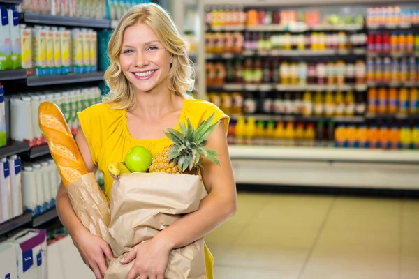 Mulher de pé no corredor com saco de supermercado — Fotografia de Stock