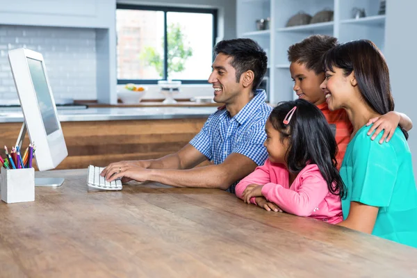 Família feliz usando o computador na cozinha — Fotografia de Stock