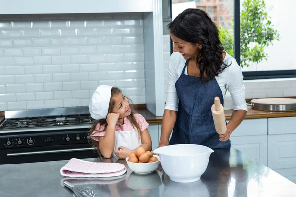 Улыбающиеся мать и дочь готовы готовить на кухне — стоковое фото