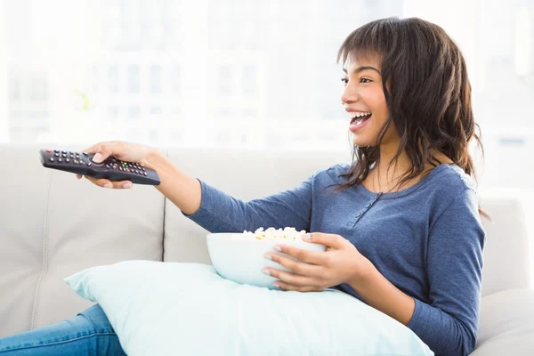 Leende casual kvinna tittar på tv med popcorn — Stockfoto