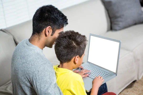 Pai e filho usando laptop no sofá — Fotografia de Stock