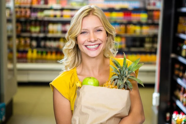 Sorrindo mulher de pé no corredor com saco de supermercado — Fotografia de Stock