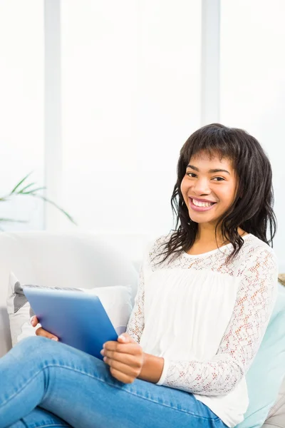 Lachende vrouw met behulp van haar tablet op Bank — Stockfoto