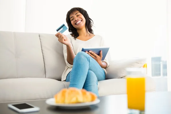 Mujer casual usando tableta mientras sostiene una tarjeta — Foto de Stock