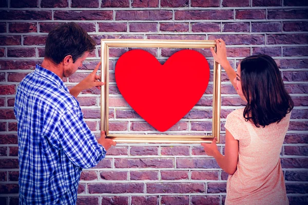 Smiling couple holding red heart shape — Stock Photo, Image